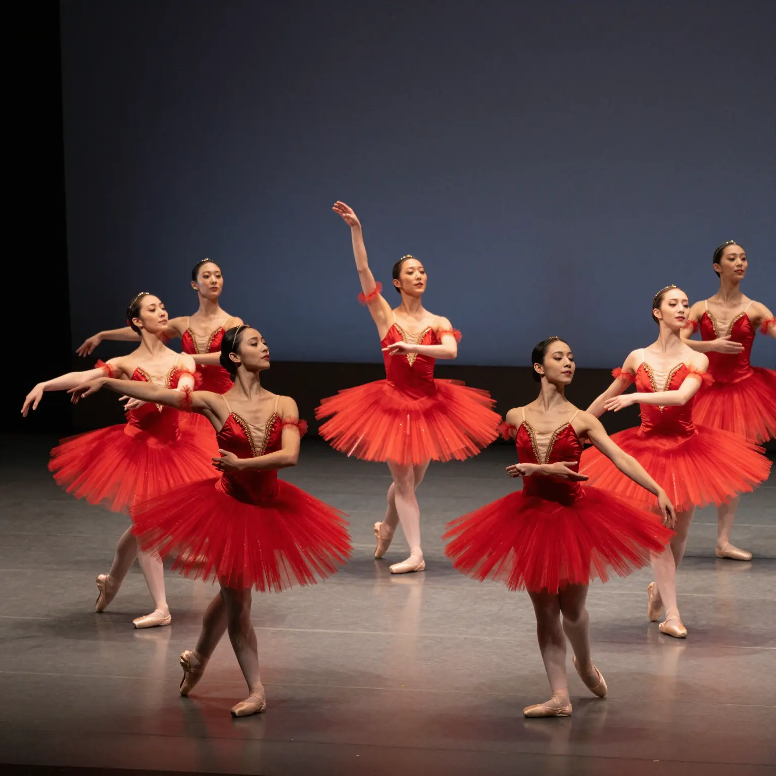 A group of dancers in red tutus performing a classic ballet piece